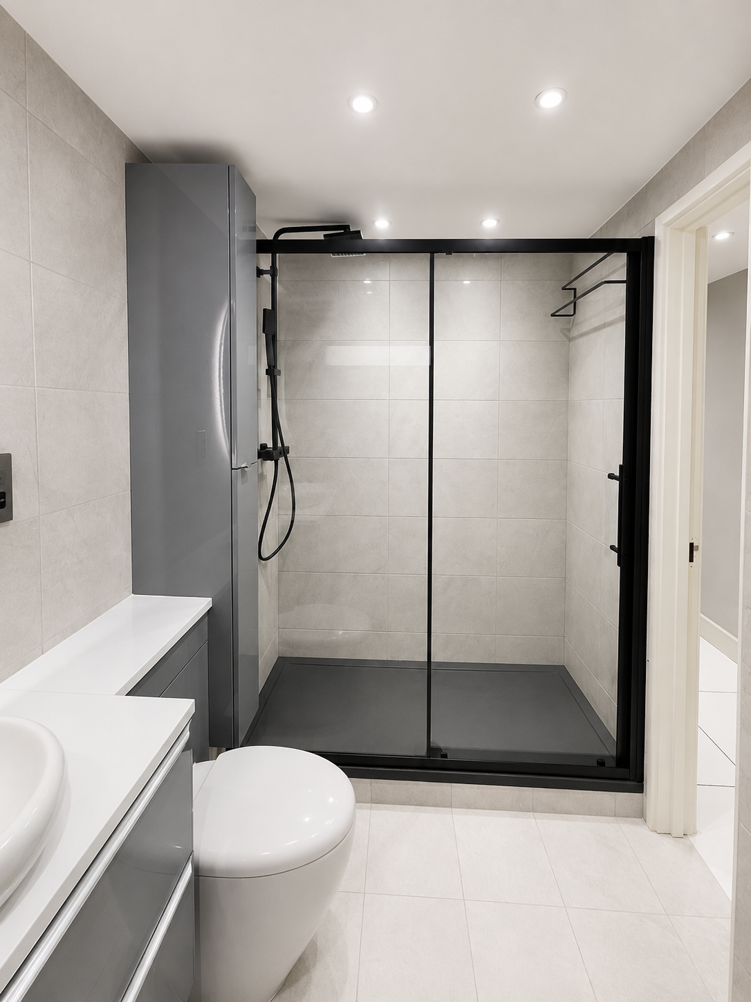 Black-framed walk-in shower with tiled walls and dark shower tray in Acton.