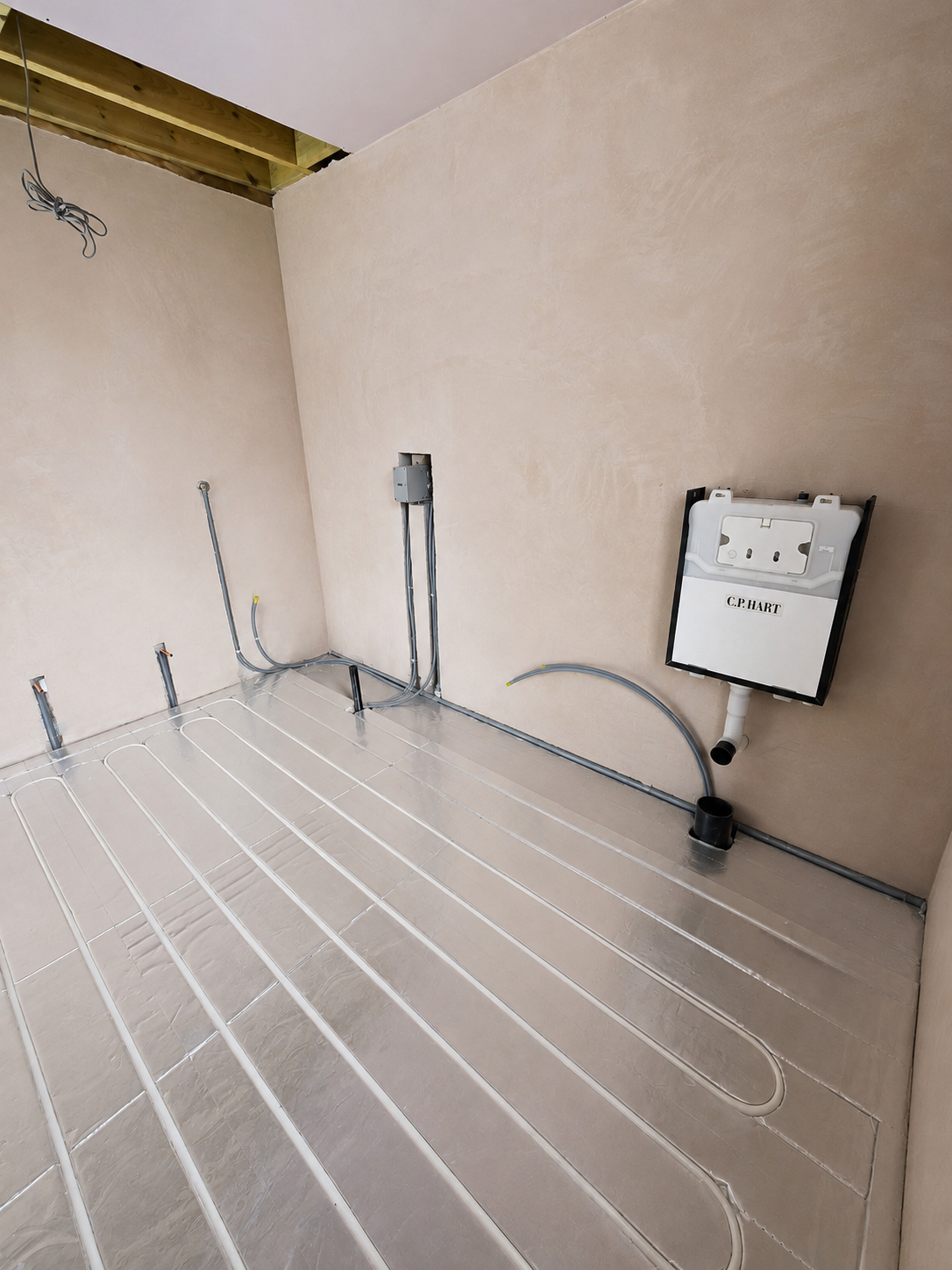 Underfloor heating pipework installed across the bathroom floor with a concealed WC frame and plumbing services.