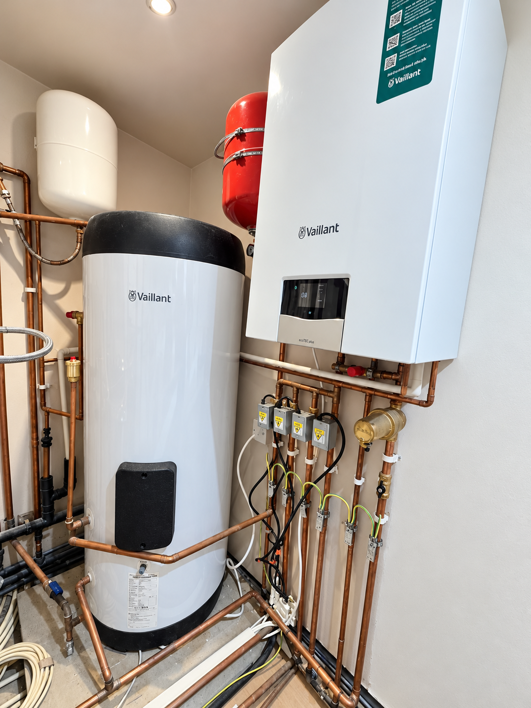 Vaillant wall-mounted boiler, hot water cylinder, expansion vessels and copper pipework in a dedicated plant room.