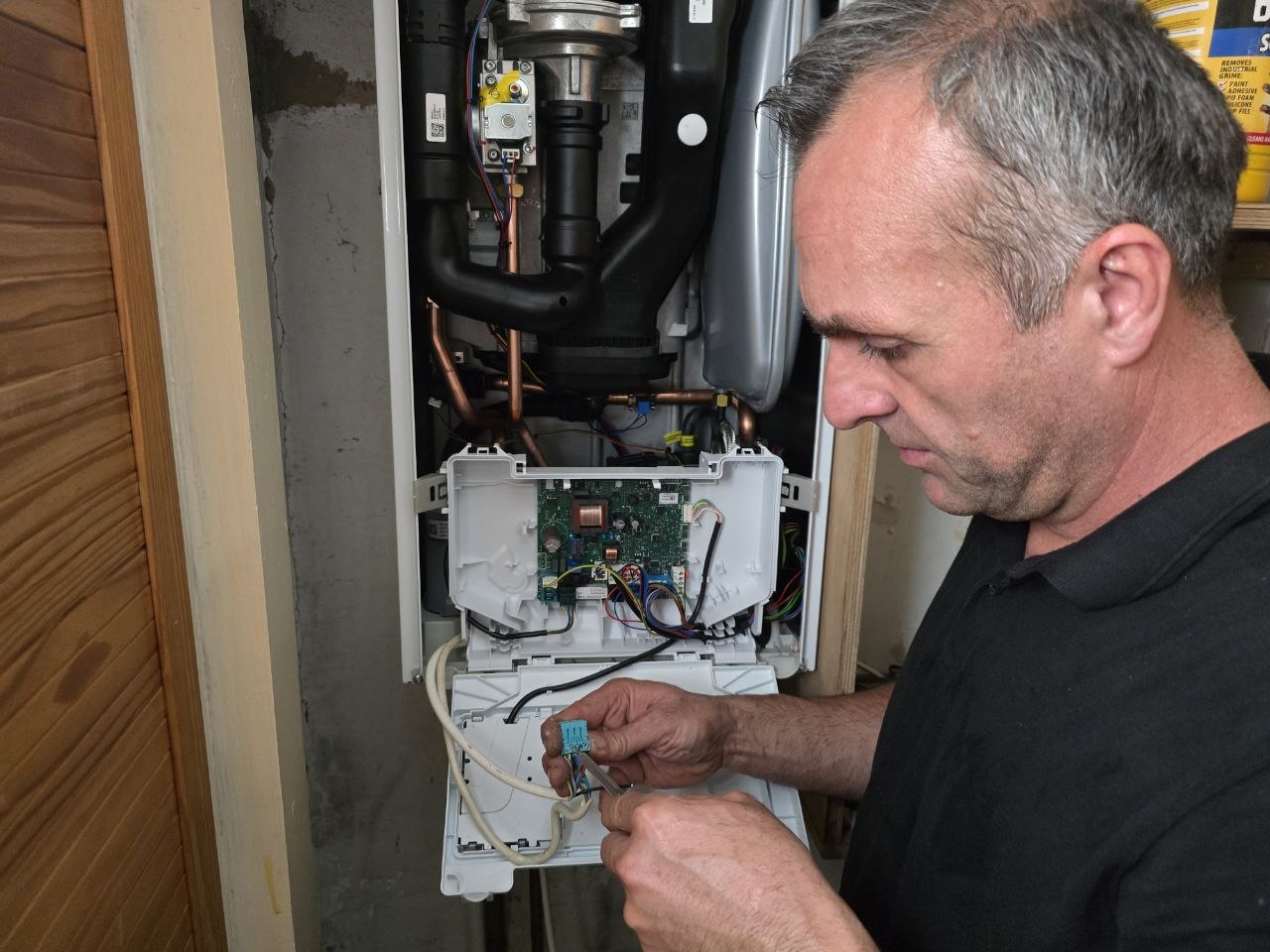 Engineer working on the internal electrical controls of the Vaillant boiler during installation.