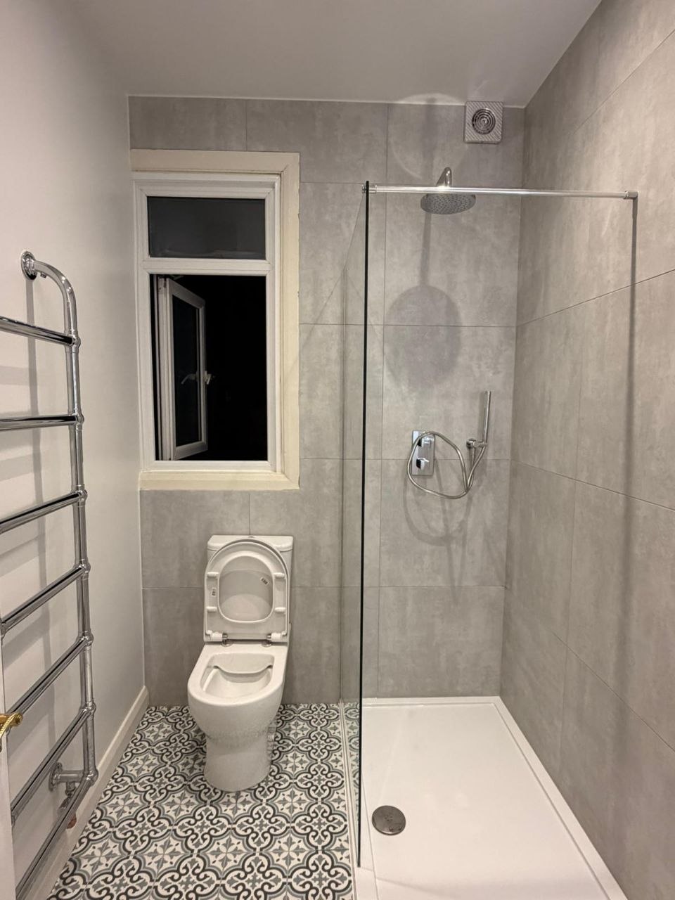 Bathroom showing walk-in shower, toilet, frosted window and chrome heated towel rail.