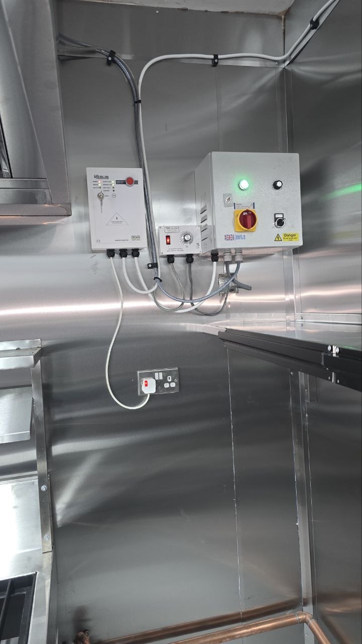 Electrical control equipment and service connections installed within a stainless-steel commercial kitchen.