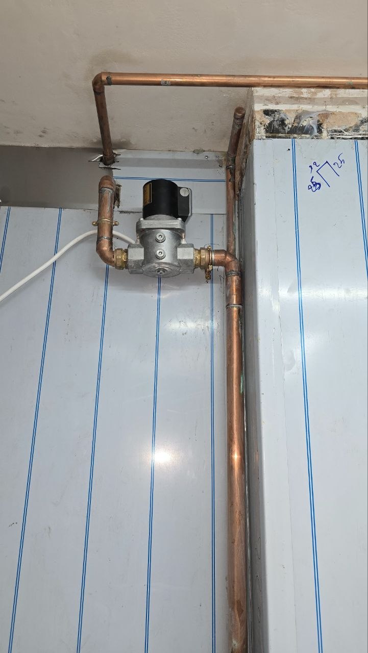 Close-up of gas control equipment connected to copper pipework in a commercial kitchen.