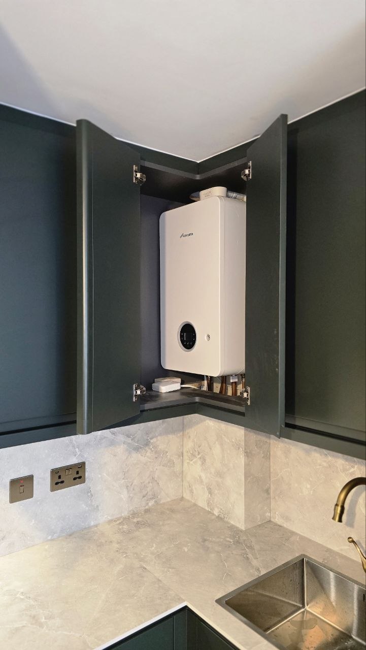 White boiler neatly enclosed inside dark kitchen cabinetry above the worktop and sink area.