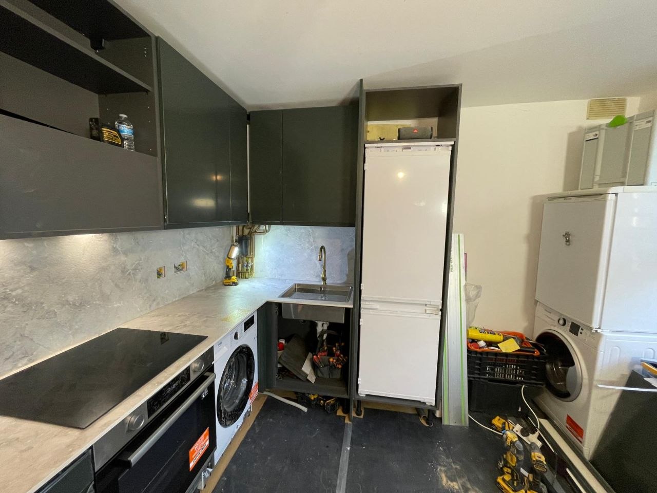 Refurbished kitchen with dark cabinets, light worktops, appliances, sink and freestanding fridge freezer.