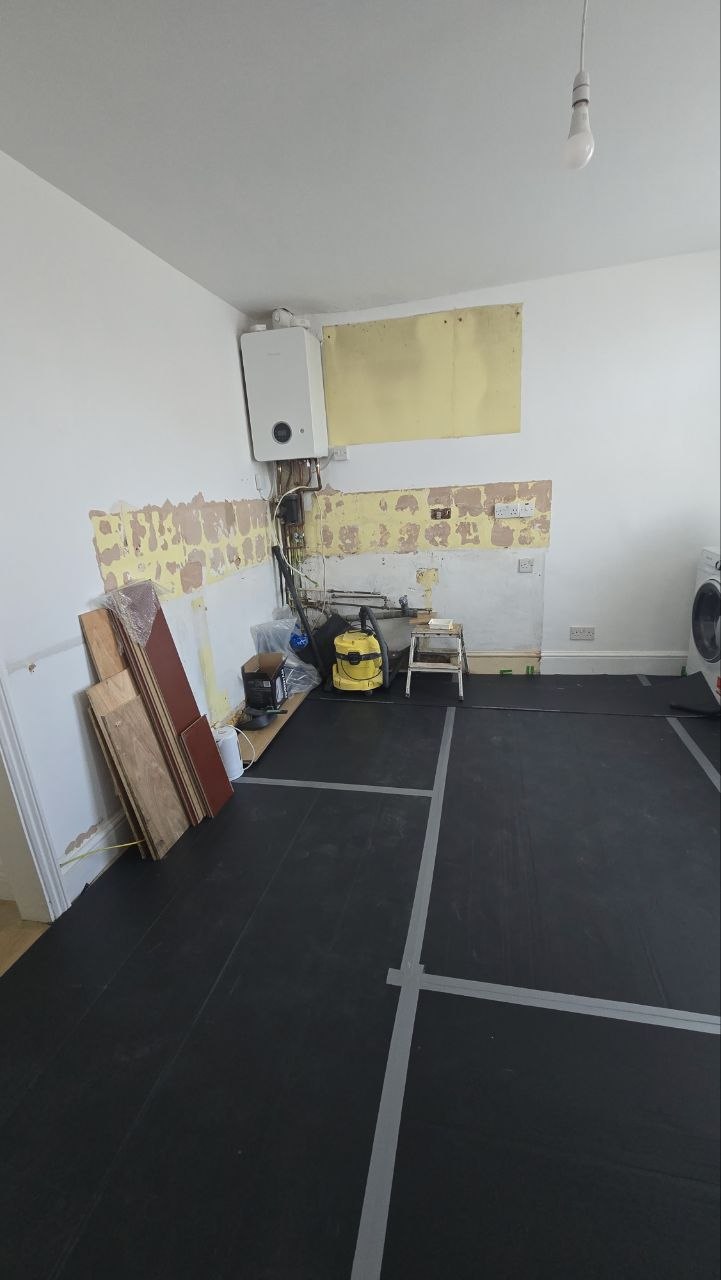 Kitchen stripped back with boiler exposed, removed finishes and materials ready for refurbishment.
