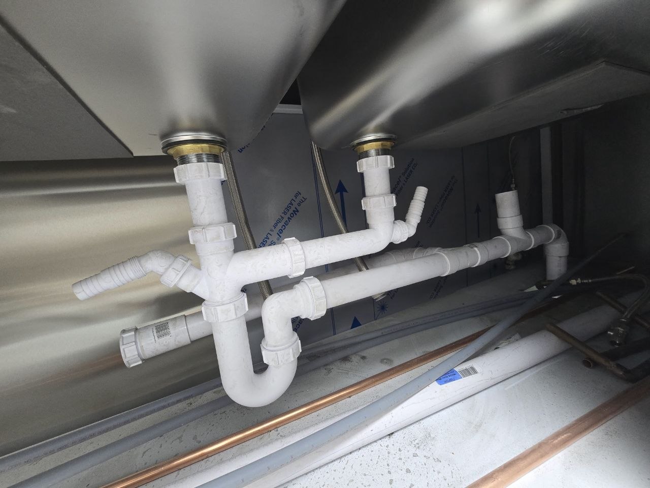 White plastic sink waste pipework and trap connected beneath a sink unit.
