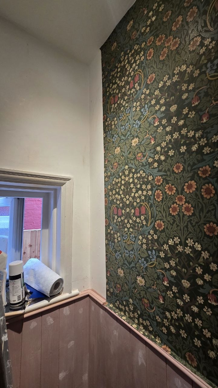 Finished cloakroom with floral wallpaper, painted timber panelling and patterned floor tiles around the window.