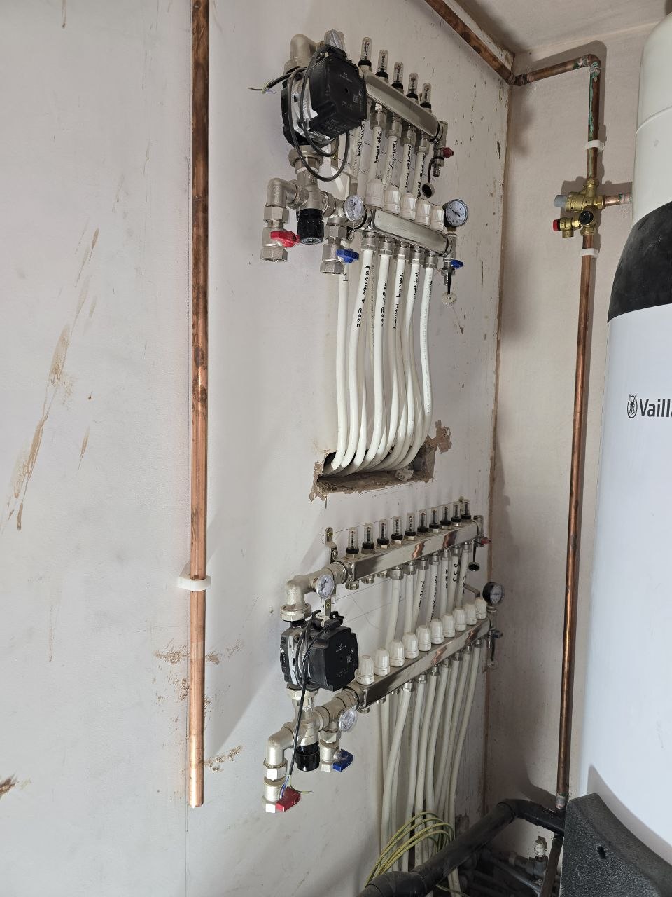 Two underfloor heating manifolds with circulation pumps, flow meters, gauges and connected pipework.